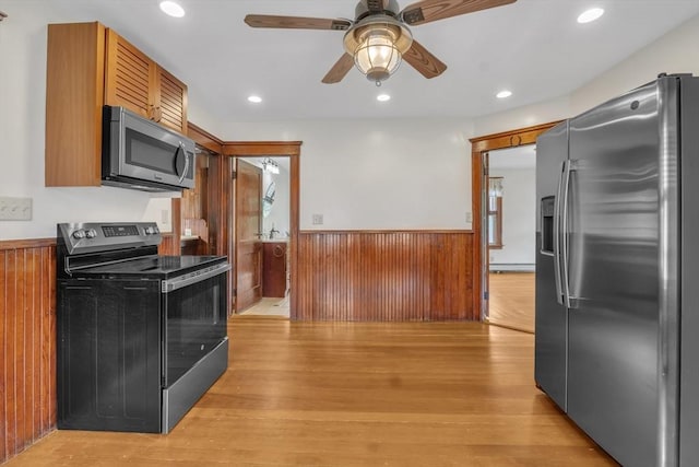 259 Main St, Blackstone, MA 01504 - kitchen featuring stainless steel appliances, a wainscoted wall, ceiling fan, wooden walls, and light wood-type flooring
