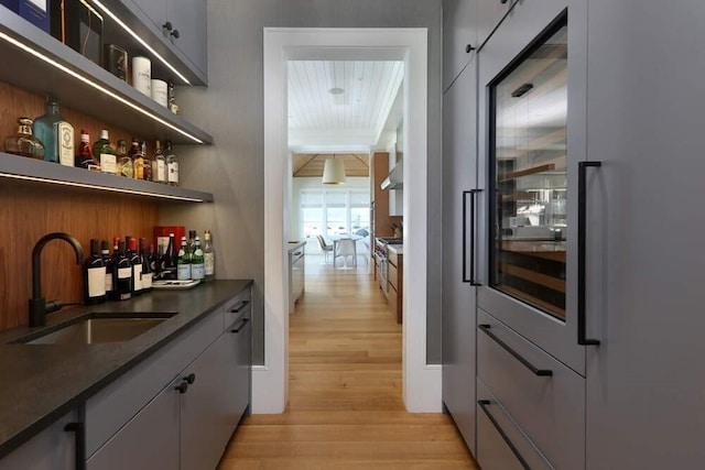 bar with beamed ceiling, wooden ceiling, sink, and light hardwood / wood-style flooring