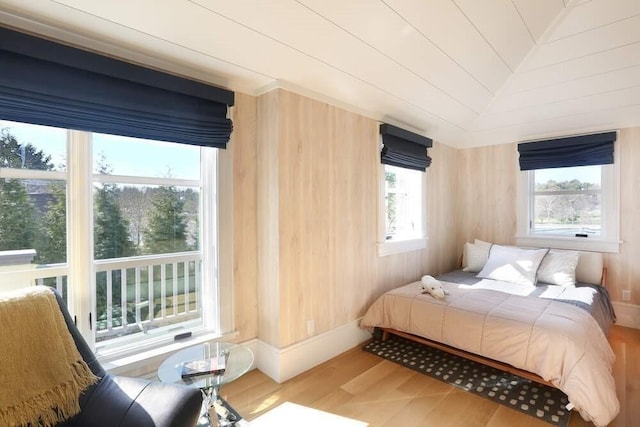 bedroom with hardwood / wood-style flooring, wooden walls, and vaulted ceiling