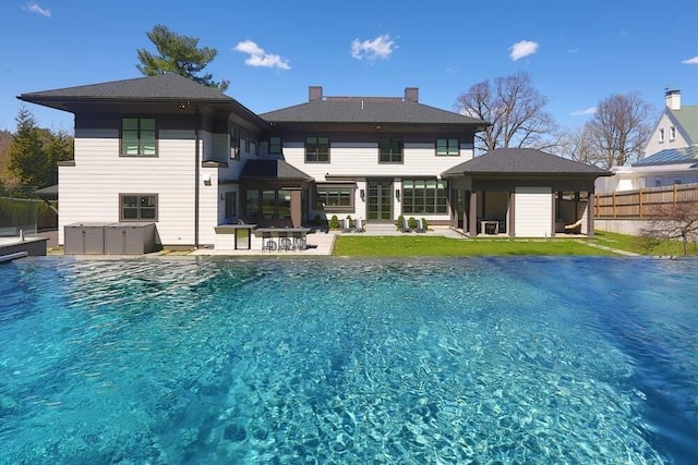 rear view of property with a swimming pool with hot tub and a patio