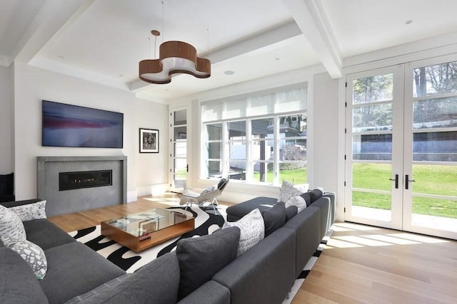 living room featuring beamed ceiling, light hardwood / wood-style flooring, and french doors