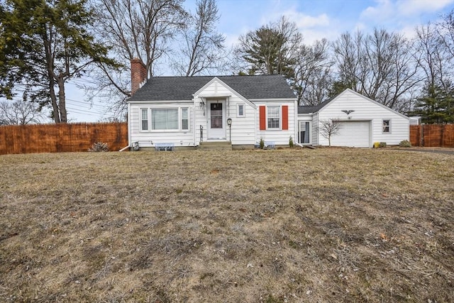 view of front facade featuring a front yard, an attached garage, fence, and a chimney