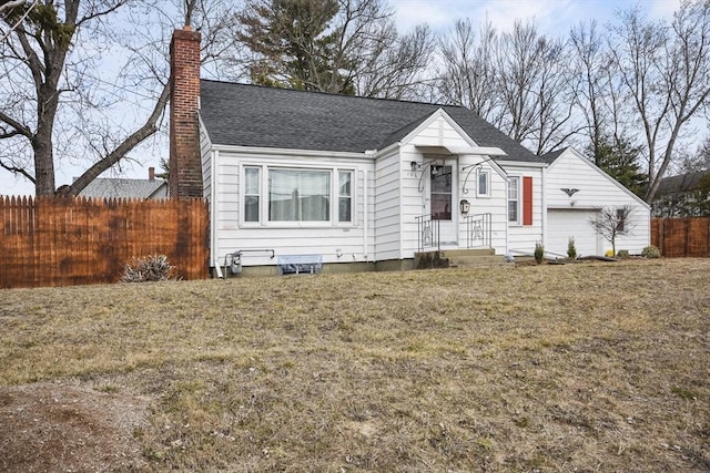 view of front of home with a front lawn, a chimney, roof with shingles, and fence