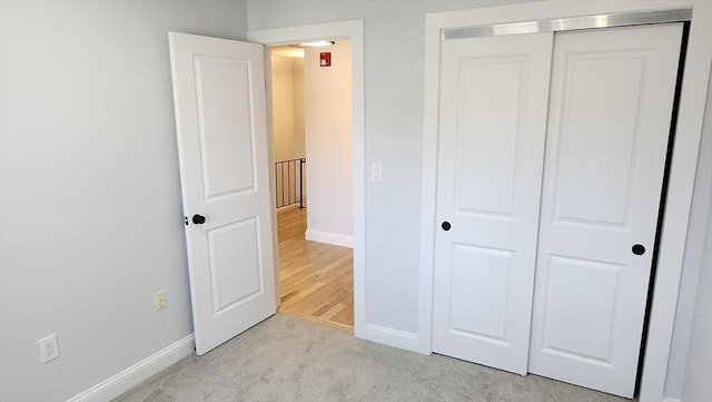 unfurnished bedroom featuring light carpet, baseboards, and a closet