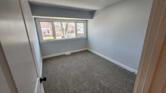 empty room with dark colored carpet and baseboards