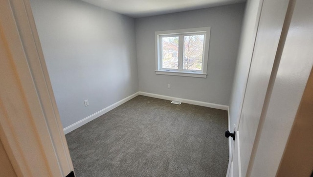spare room featuring dark colored carpet and baseboards