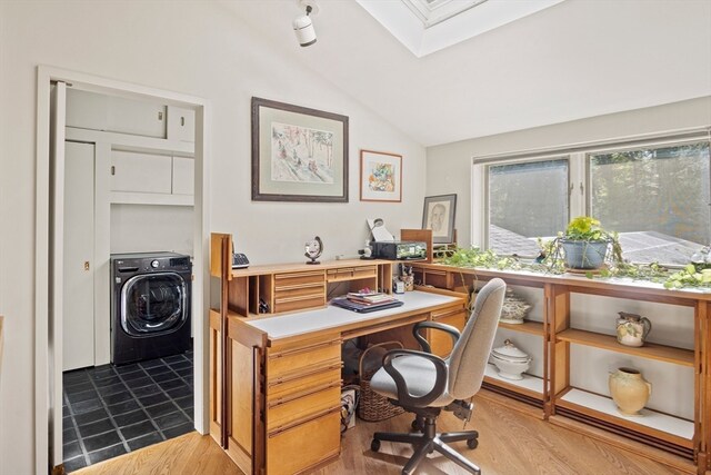 office area featuring washer / clothes dryer, vaulted ceiling with skylight, and light wood-type flooring