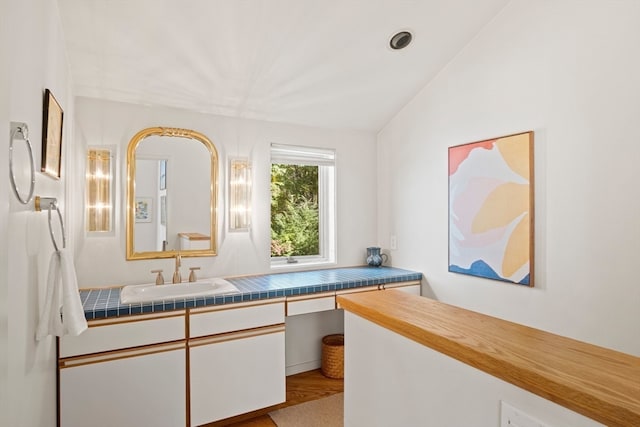 bathroom with hardwood / wood-style flooring, vanity, and vaulted ceiling