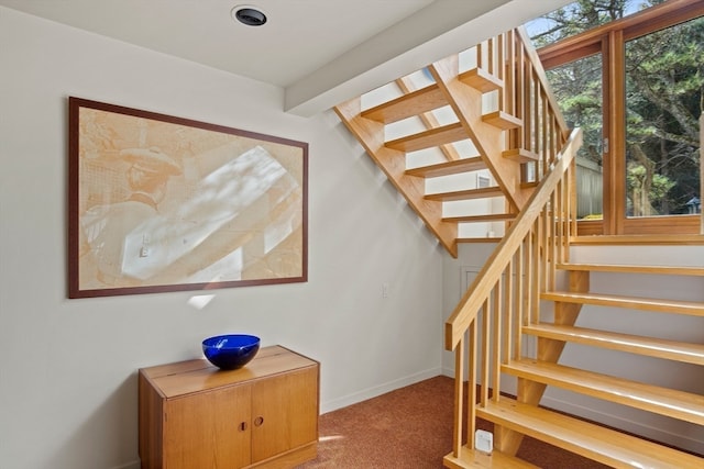 stairway with carpet floors and beam ceiling