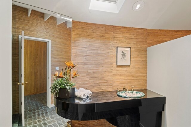 dining area featuring lofted ceiling with skylight and wood walls