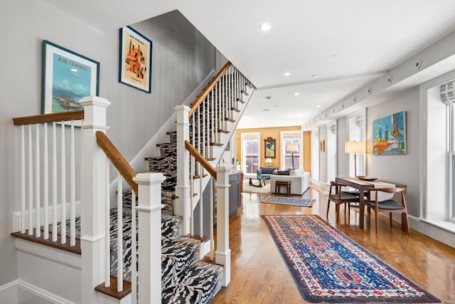stairs featuring wood finished floors and recessed lighting