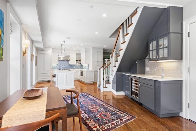 kitchen featuring wine cooler, gray cabinetry, a sink, backsplash, and light countertops