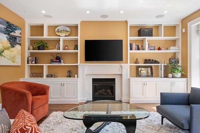 living area featuring wood finished floors, a premium fireplace, and built in features