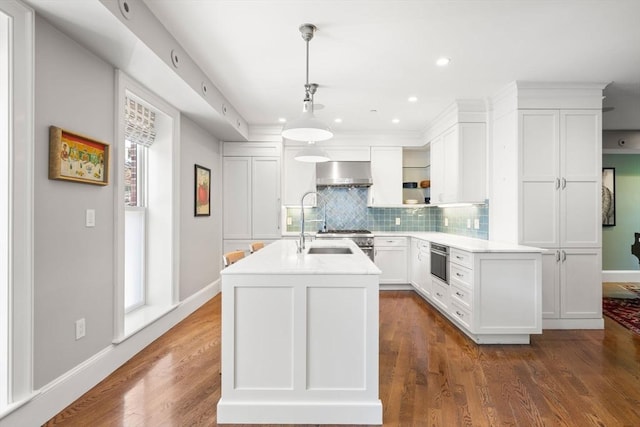 kitchen with extractor fan, white cabinets, tasteful backsplash, light countertops, and an island with sink