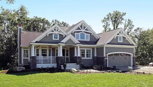 craftsman-style home with covered porch, a front yard, and a garage