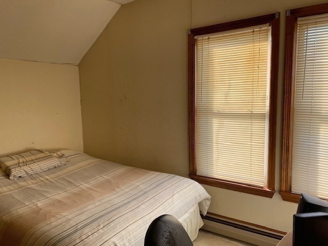 bedroom with baseboard heating and lofted ceiling