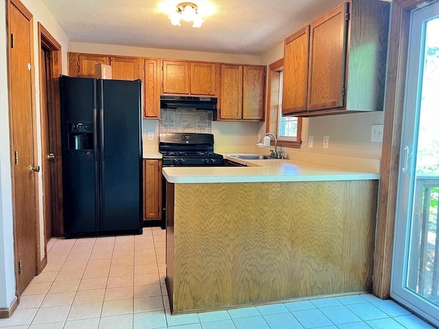 80 Smith St Unit 2A, Lowell, MA 01851 - kitchen with black appliances, a sink, under cabinet range hood, brown cabinets, and a textured ceiling