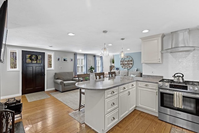 28 Manomet Beach Blvd, Plymouth, MA 02360 - kitchen featuring stainless steel gas range oven, wall chimney range hood, open floor plan, a breakfast bar, and a peninsula