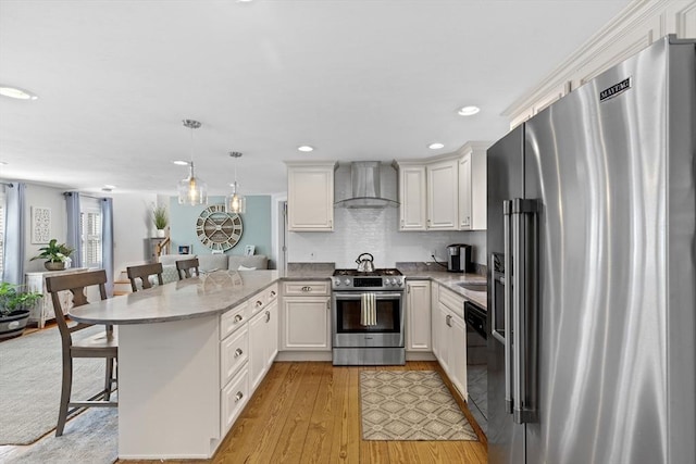 28 Manomet Beach Blvd, Plymouth, MA 02360 - kitchen featuring stainless steel appliances, wall chimney range hood, a peninsula, a kitchen bar, and white cabinetry