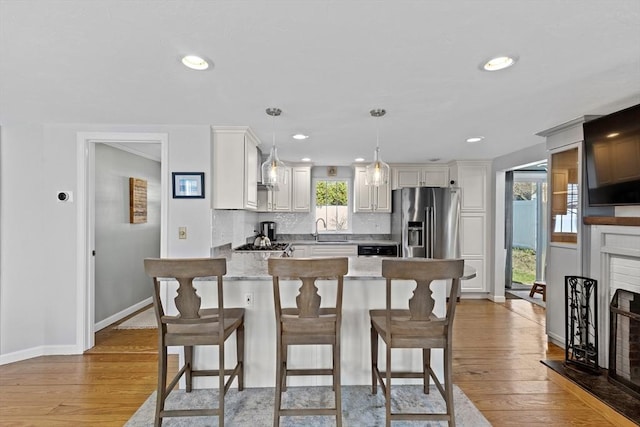 28 Manomet Beach Blvd, Plymouth, MA 02360 - kitchen featuring stainless steel fridge, a peninsula, a sink, a brick fireplace, and a kitchen bar