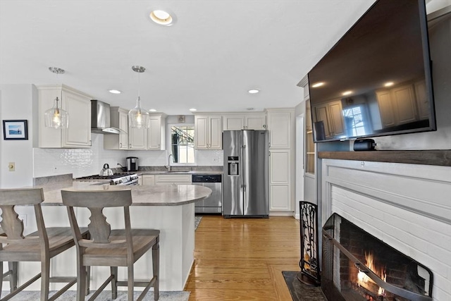 28 Manomet Beach Blvd, Plymouth, MA 02360 - kitchen featuring appliances with stainless steel finishes, a sink, wall chimney range hood, a peninsula, and hanging light fixtures