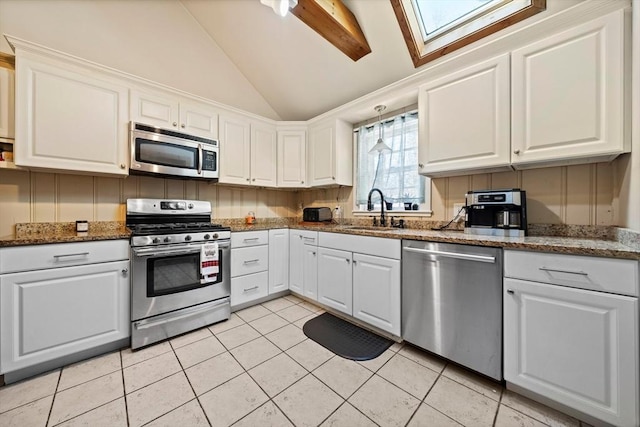 kitchen featuring appliances with stainless steel finishes, white cabinets, sink, dark stone counters, and light tile patterned flooring