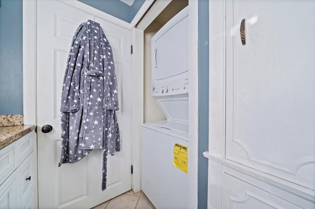 laundry room featuring stacked washer / drying machine and light tile patterned flooring