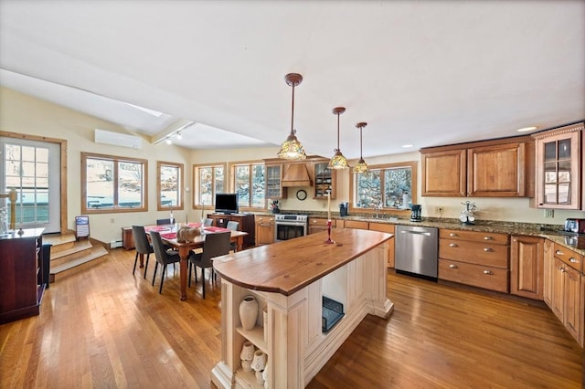 kitchen featuring appliances with stainless steel finishes, a wall mounted air conditioner, hanging light fixtures, vaulted ceiling with beams, and butcher block countertops