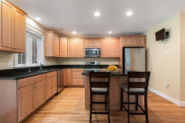 kitchen featuring sink, a center island, dark stone counters, light wood-type flooring, and stainless steel appliances