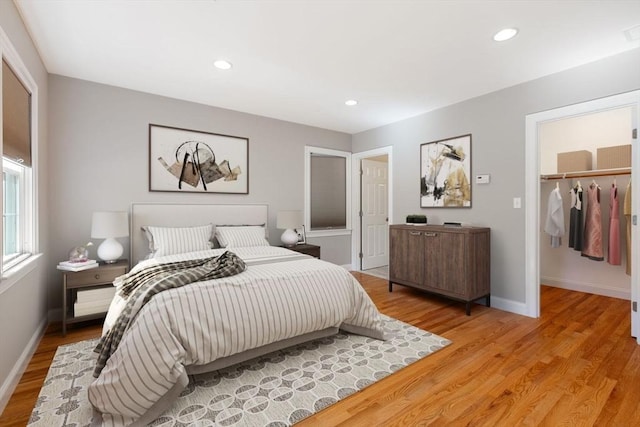 bedroom with a walk in closet, light hardwood / wood-style floors, and a closet