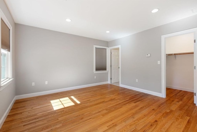 unfurnished bedroom featuring a closet, a spacious closet, and light hardwood / wood-style flooring