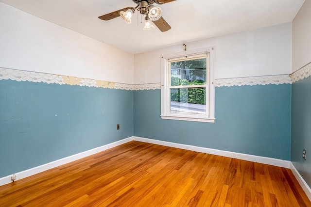 spare room with ceiling fan, wood finished floors, and baseboards
