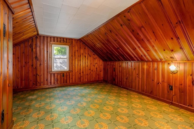 bonus room with wood walls, lofted ceiling, and baseboards