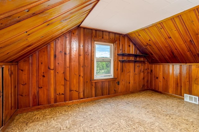 additional living space featuring lofted ceiling, baseboards, and wood walls