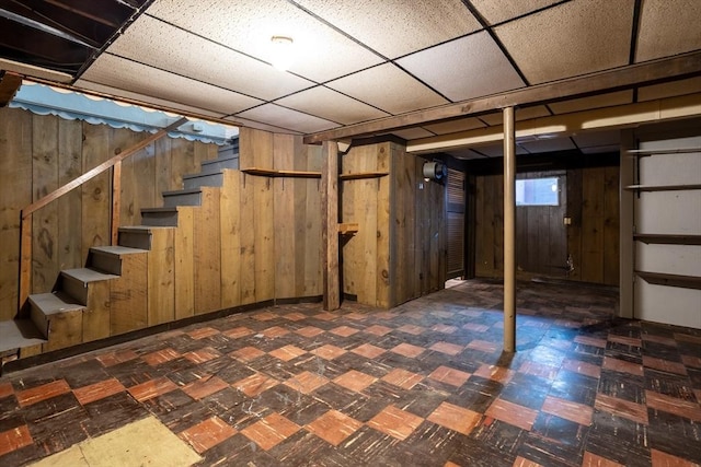 below grade area featuring tile patterned floors, wood walls, and stairway