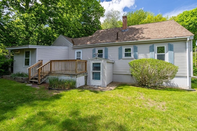 rear view of property with a deck, a chimney, and a yard