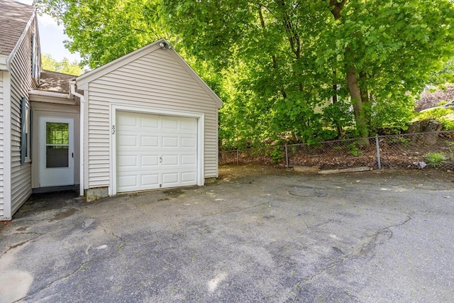 garage with fence and asphalt driveway