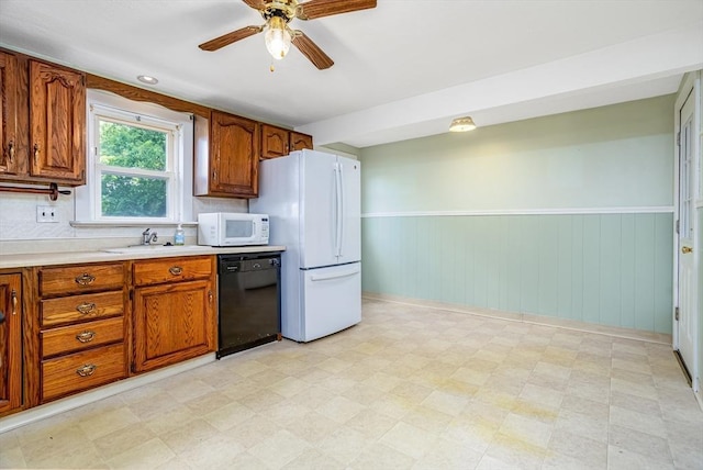 kitchen featuring white appliances, a sink, brown cabinetry, ceiling fan, and light flooring