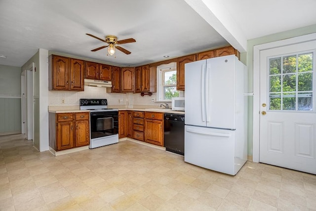 kitchen with white appliances, under cabinet range hood, brown cabinets, light countertops, and ceiling fan