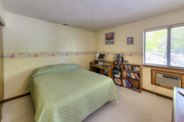 carpeted bedroom featuring wallpapered walls, a wall mounted AC, and baseboards