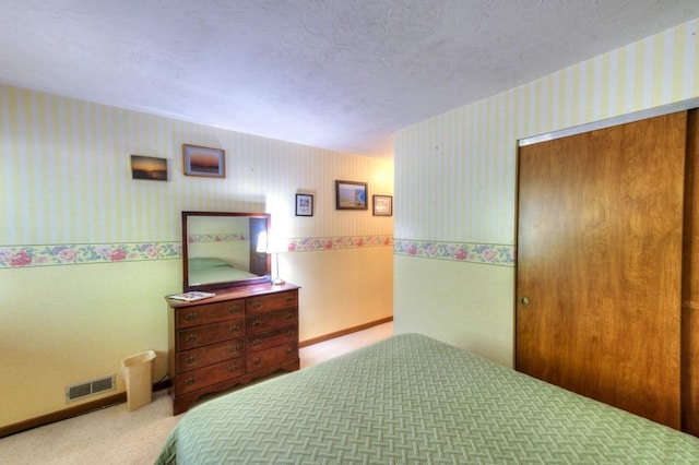 bedroom with wallpapered walls, carpet flooring, and a closet
