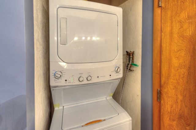 clothes washing area with estacked washer and dryer and a textured wall
