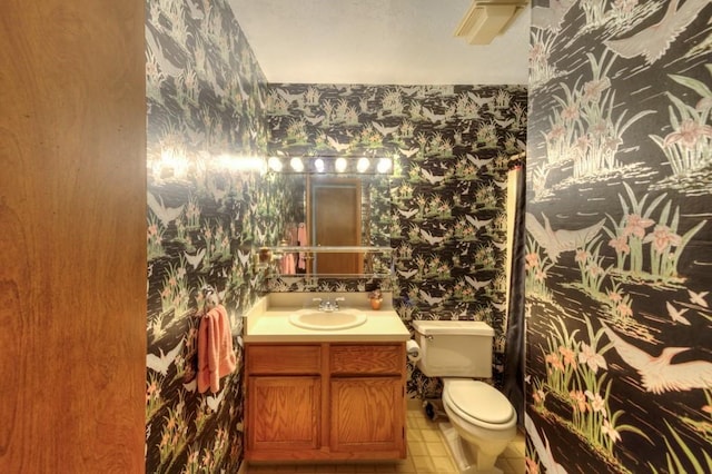 bathroom with wallpapered walls, toilet, and vanity