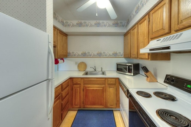 kitchen with electric stove, freestanding refrigerator, stainless steel microwave, a sink, and under cabinet range hood