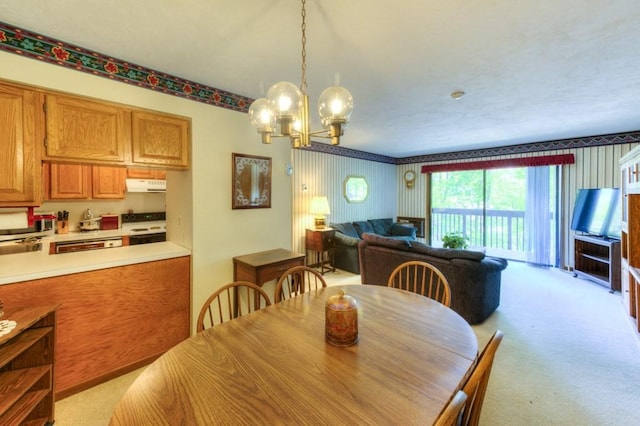 dining room with a chandelier, light carpet, and wallpapered walls