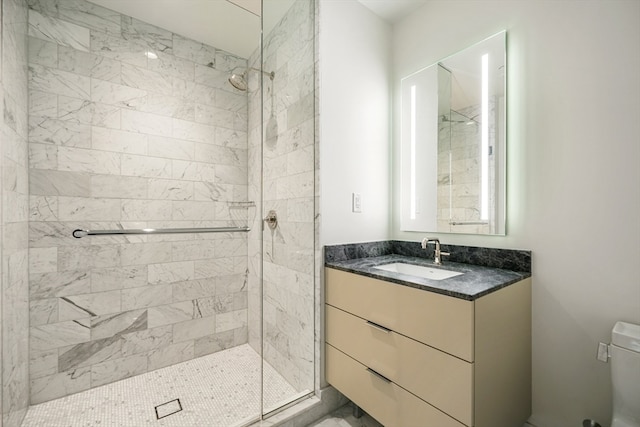 bathroom with vanity, a tile shower, and toilet