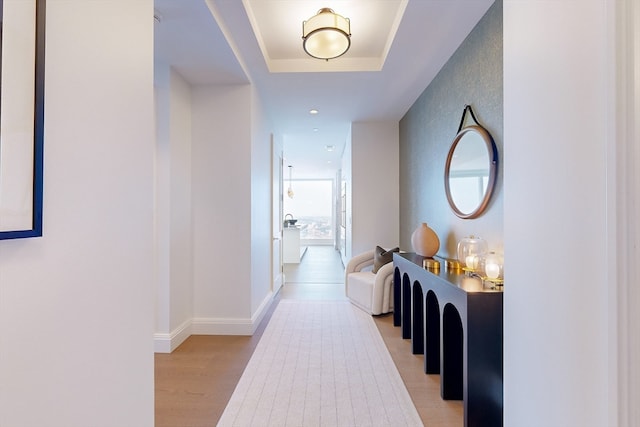 hallway featuring light hardwood / wood-style floors and a raised ceiling