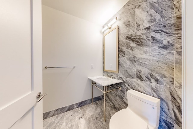 bathroom with toilet, tile walls, and sink