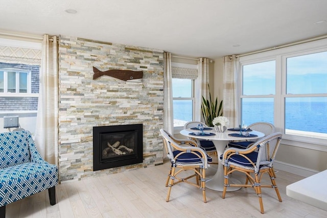 118 Oceanside Dr, Scituate, MA 02066 - dining room featuring wood finished floors, a stone fireplace, a water view, and baseboards