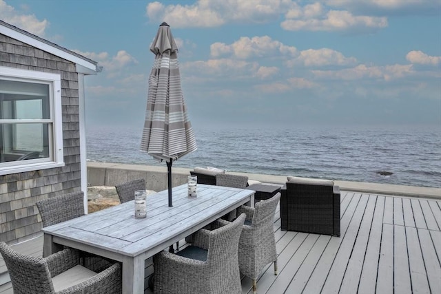 deck with a water view and outdoor dining area